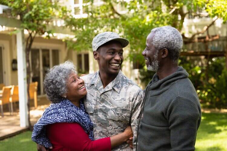 Un soldado se abraza y sonríe con sus padres.